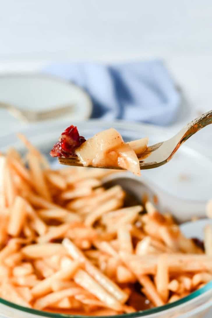 fork holding some slaw with more in a bowl underneath it.