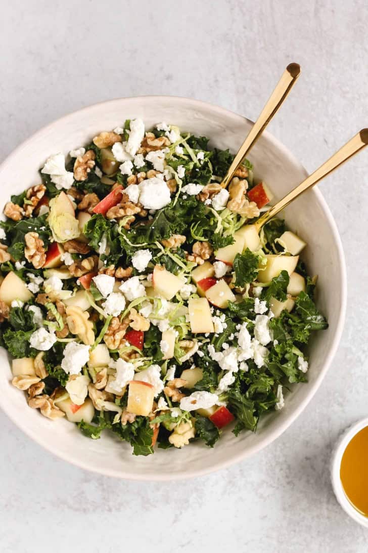 overhead of salad in a white bowl with two serving spoons in it.