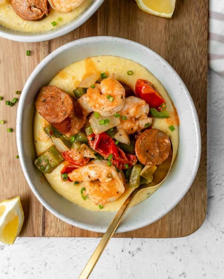 overhead of shrimp and grits with sausage in a white bowl with a spoon in it.