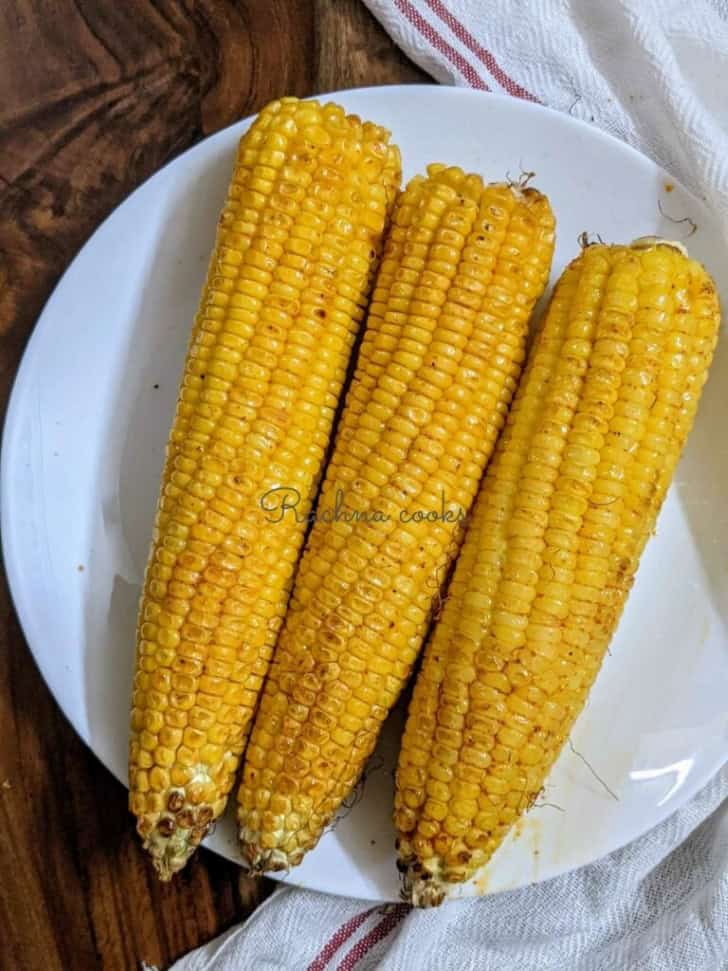 three ears of air fryer corn on the cob on a plate.