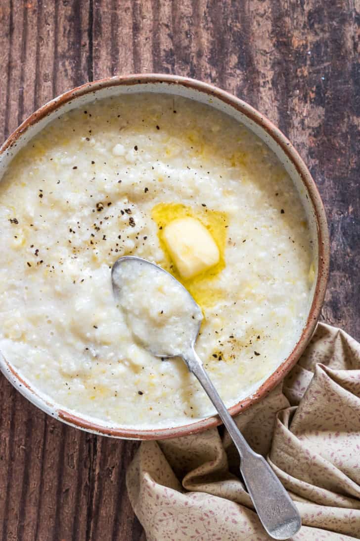 overhead of grits in a bowl with butter pat and a spoon in it.