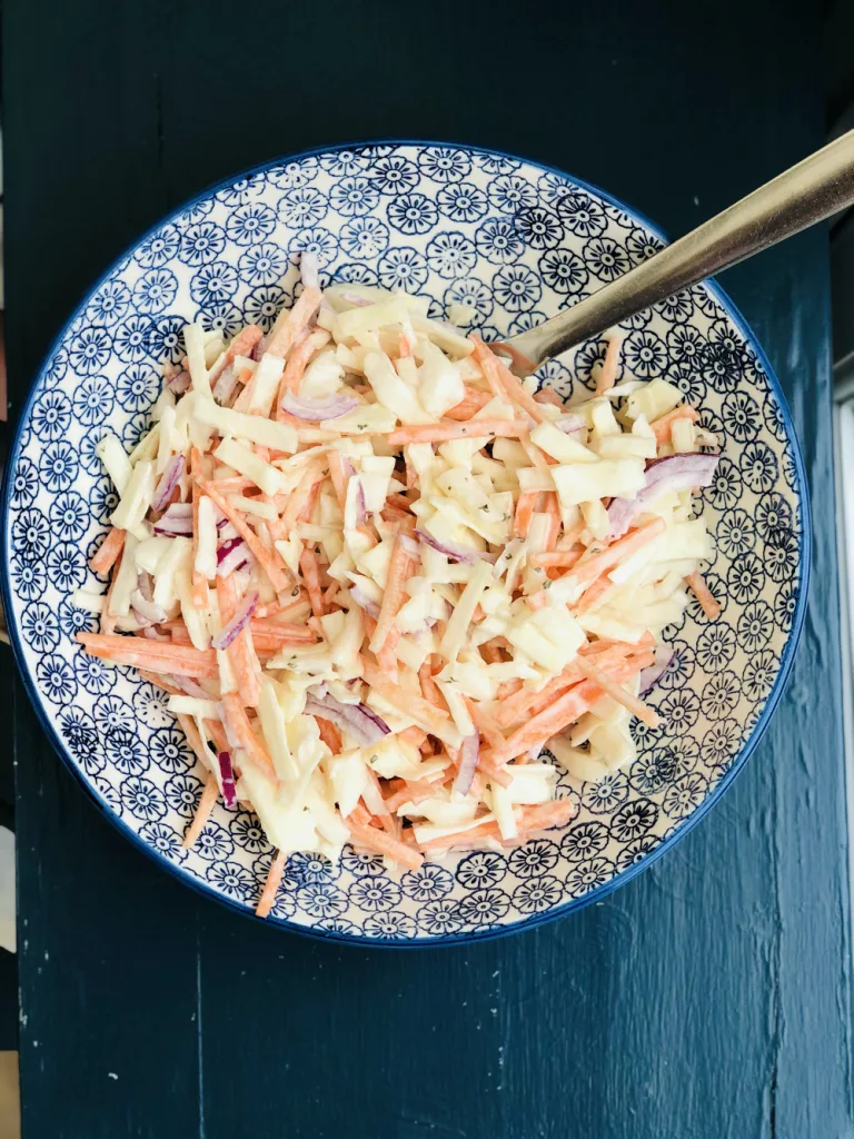 overhead of ranch coleslaw in a decorative bowl with a spoon in it.