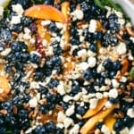 pin showing overhead close-up of blueberry and peach arugula salad with title text overlay.