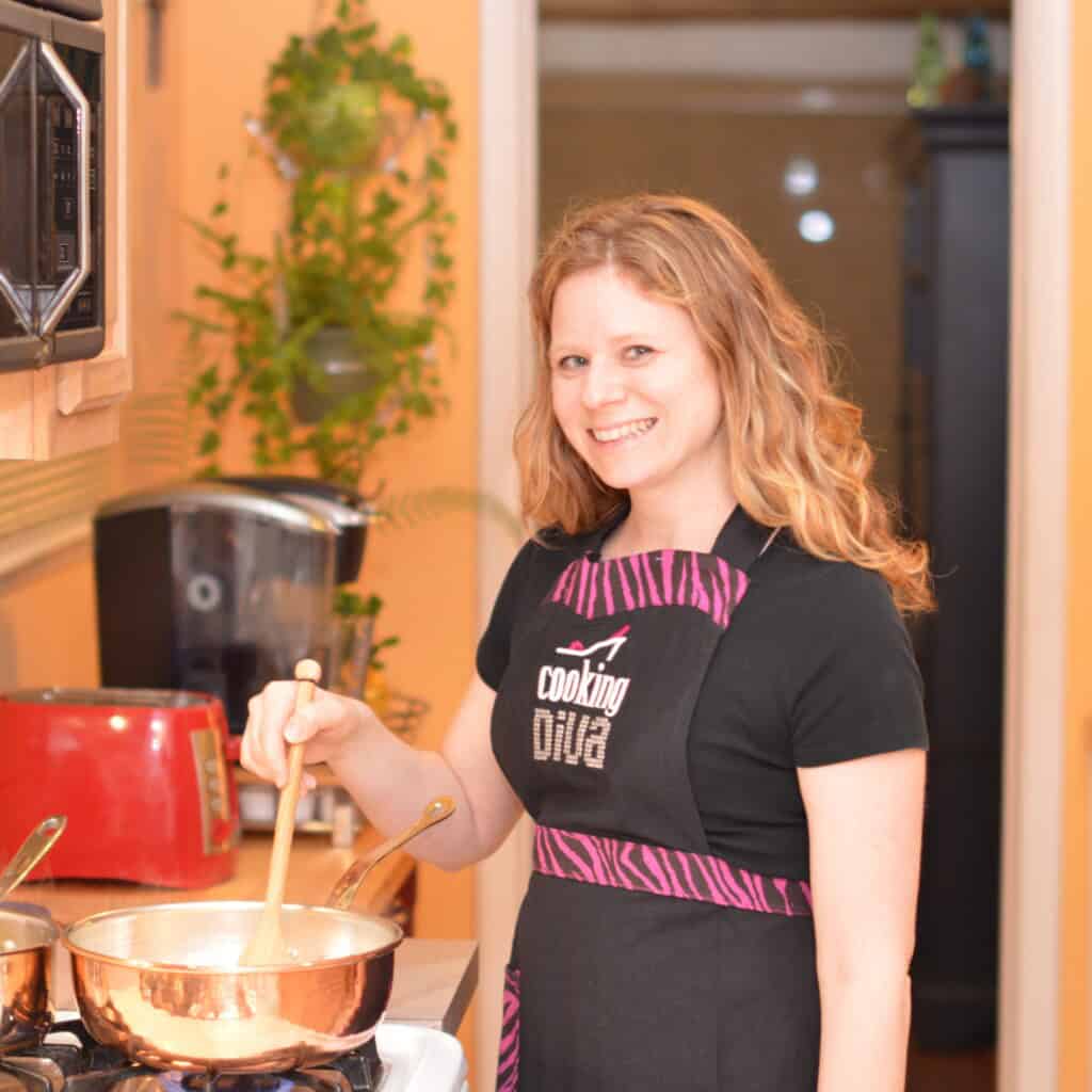 Sherri wearing apron and stirring food in a pot on the stovetop.