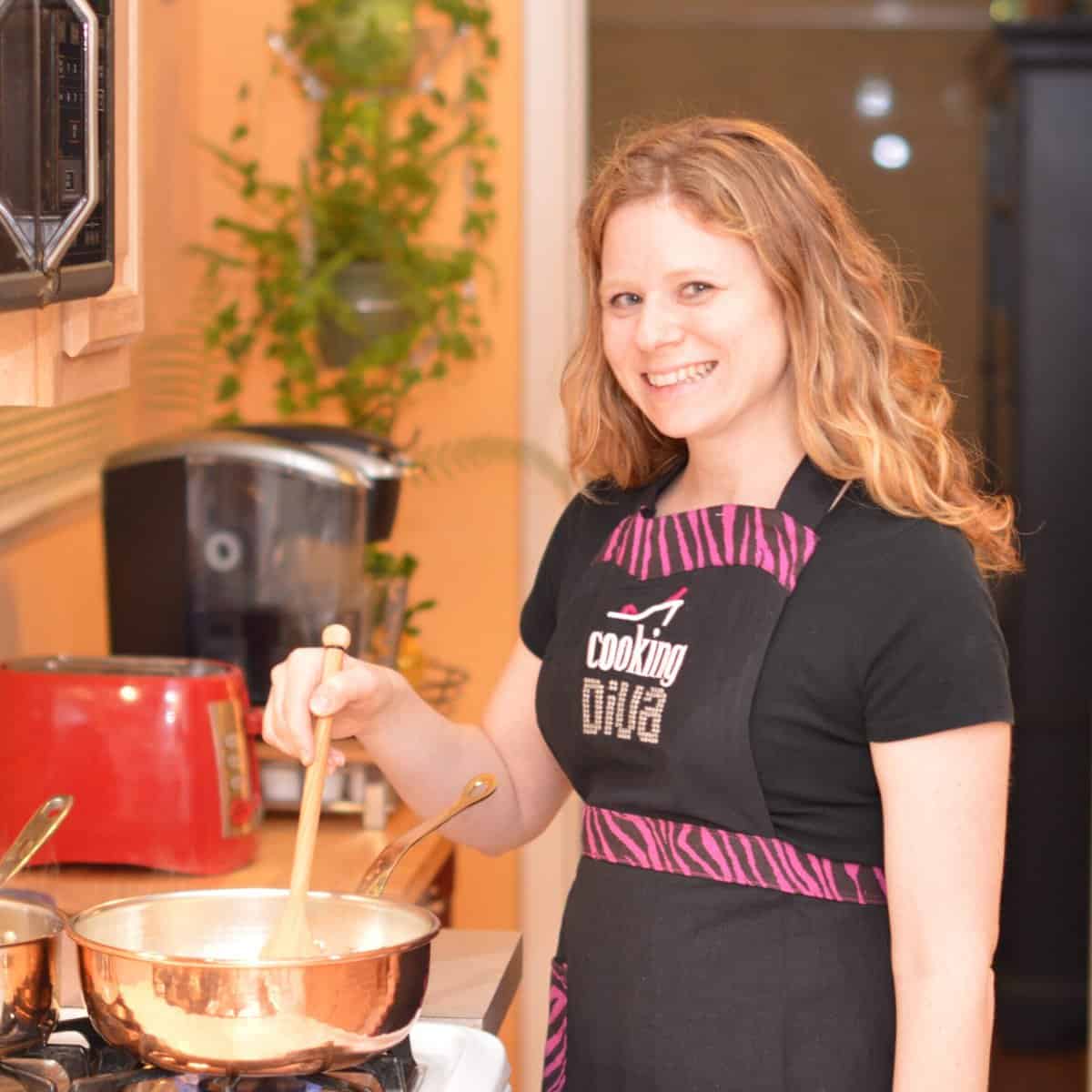 Sherri wearing apron and stirring food in a pot on the stovetop.