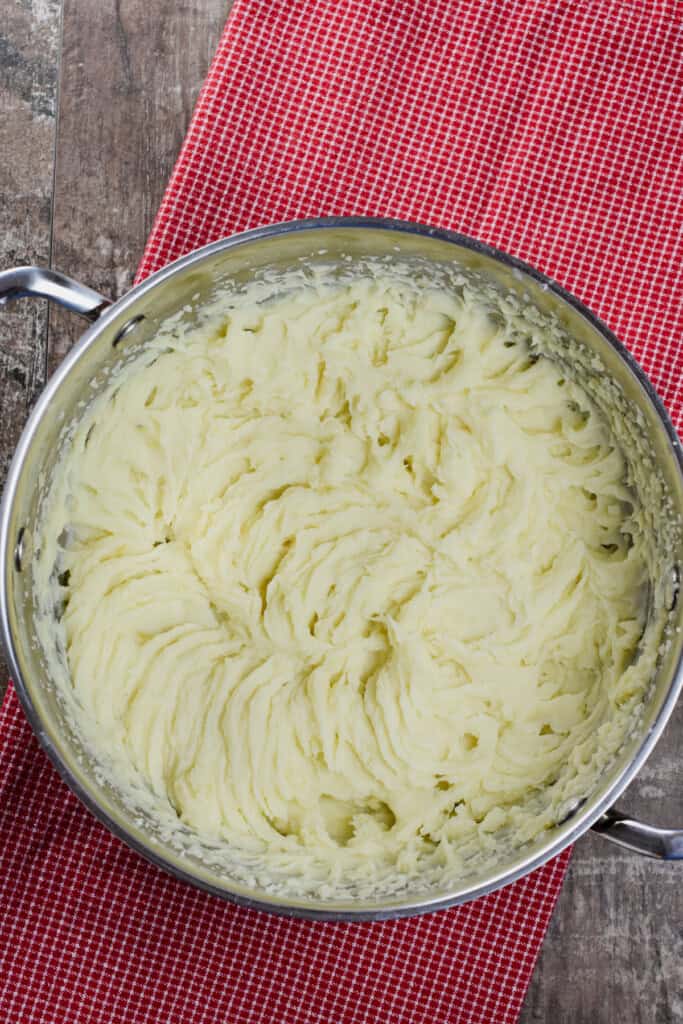 overhead of mashed potatoes in a pot after whipping with an electric mixer.