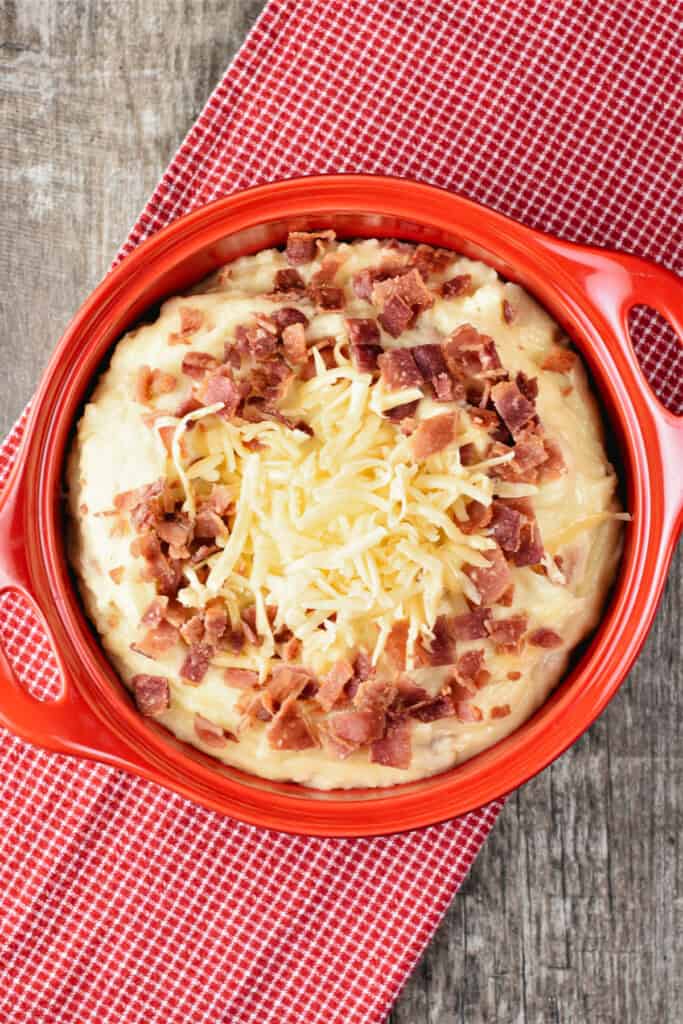 overhead of mashed potatoes with more bacon and cheese on top in a circular baking dish.