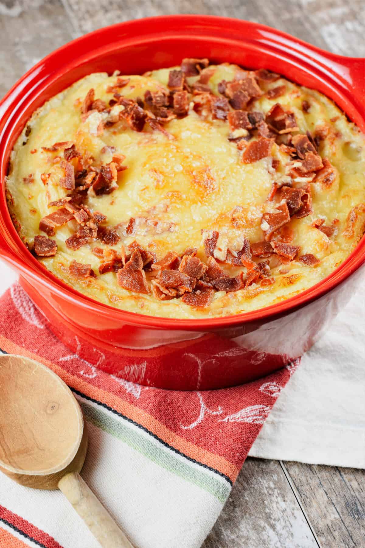 mashed potatoes with bacon and cheese after baking in a red circular baking dish.