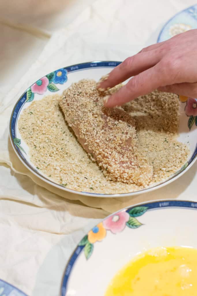 coating chicken breast fillet in breadcrumbs.