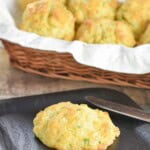 Pinterest pin showing a biscuit on a plate with more behind it in a basket and text title overlay.