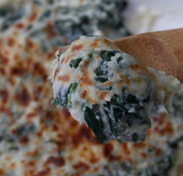 Scooping out some low-carb cauliflower creamed spinach with a wooden spoon.