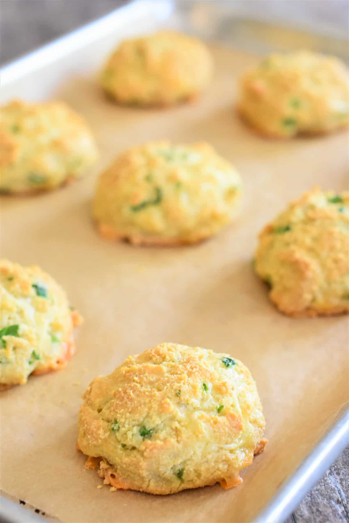 Jalapeno cheddar biscuits on a parchment-lined baking sheet.