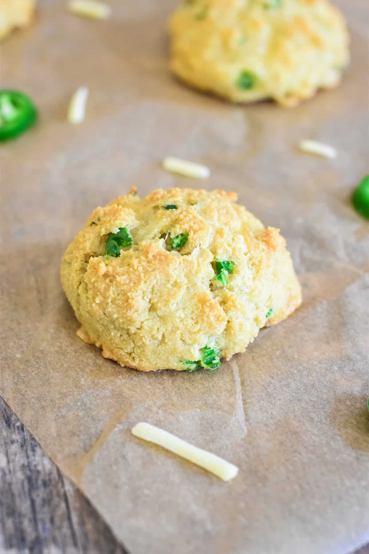 Close-up of a jalapeno cheddar almond flour biscuit on parchment paper.