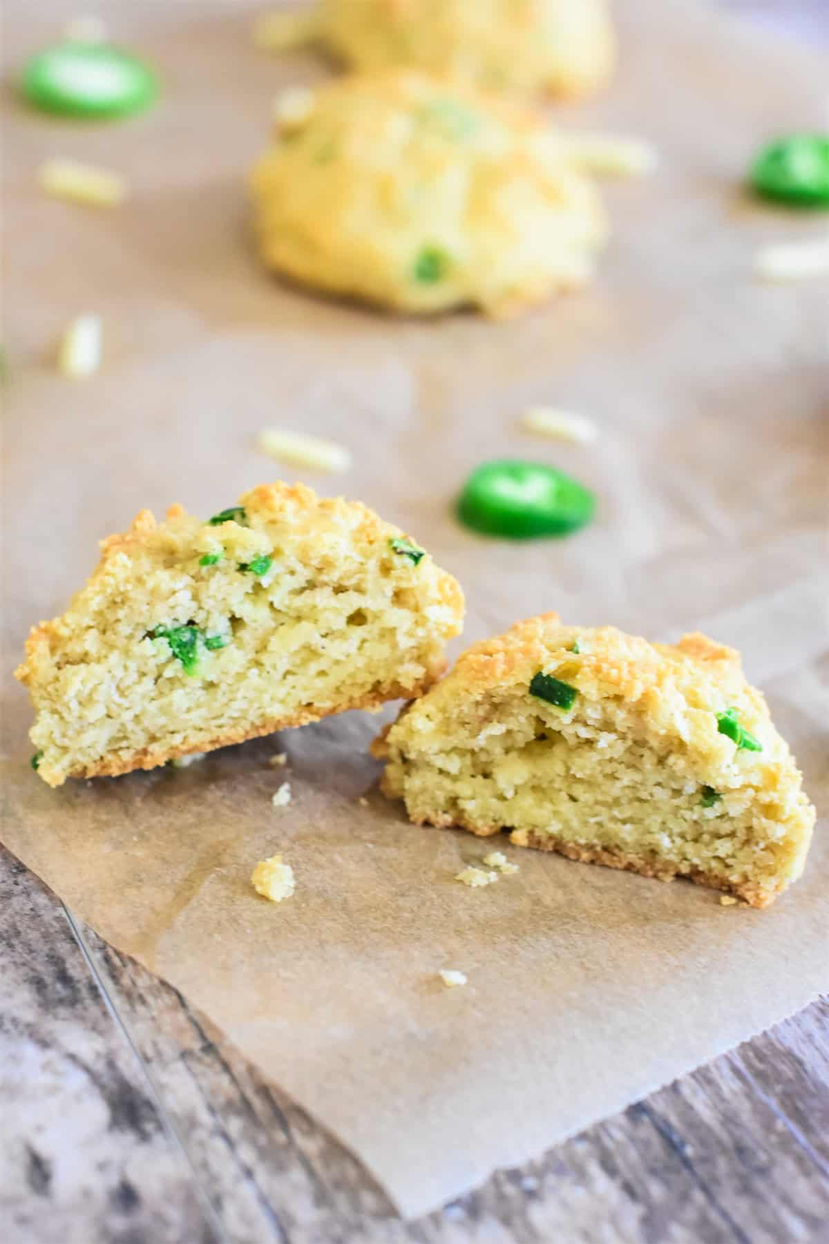 An open jalapeno cheddar biscuit on parchment paper with more behind it.