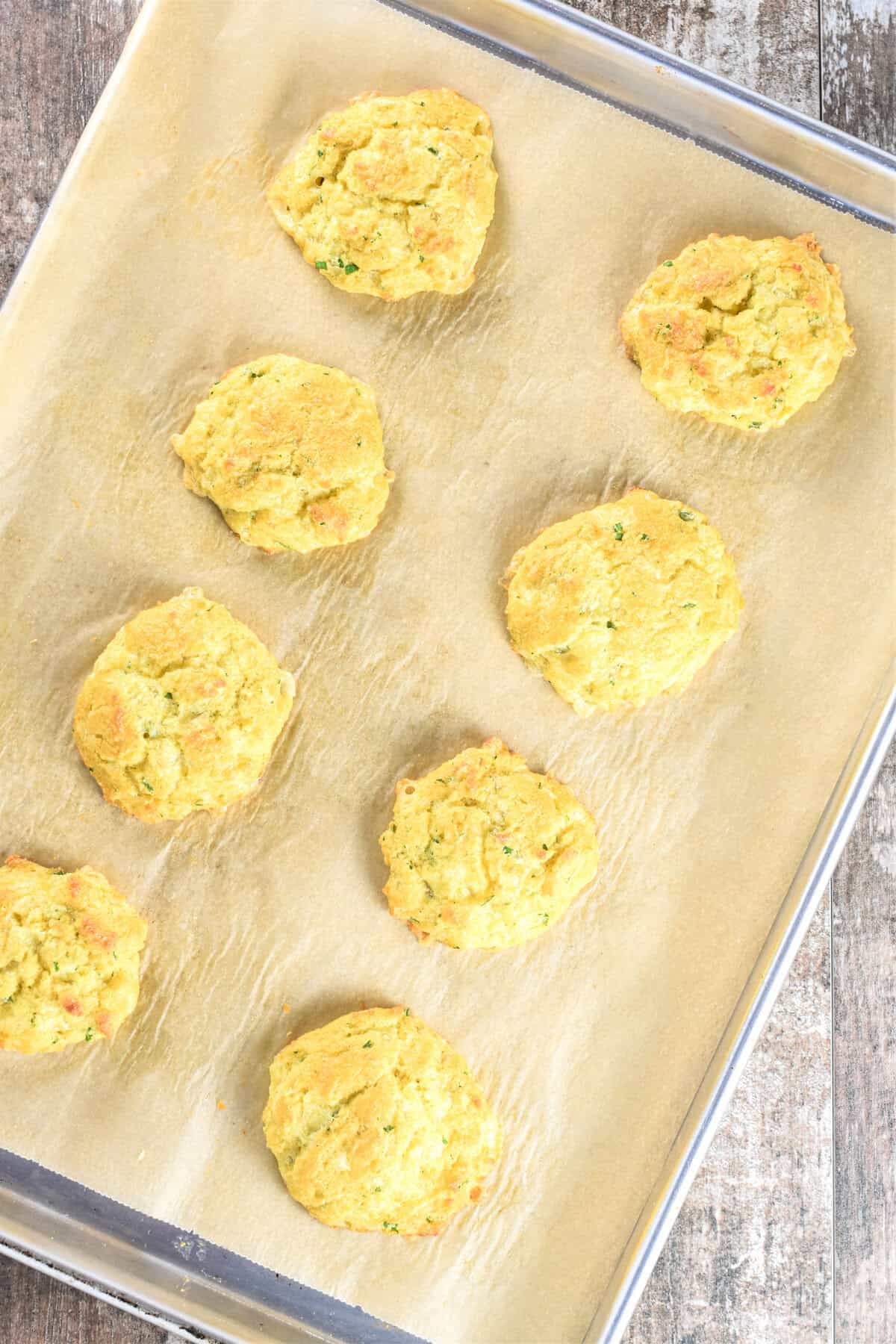 Keto biscuits on a parchment-lined baking sheet after baking.