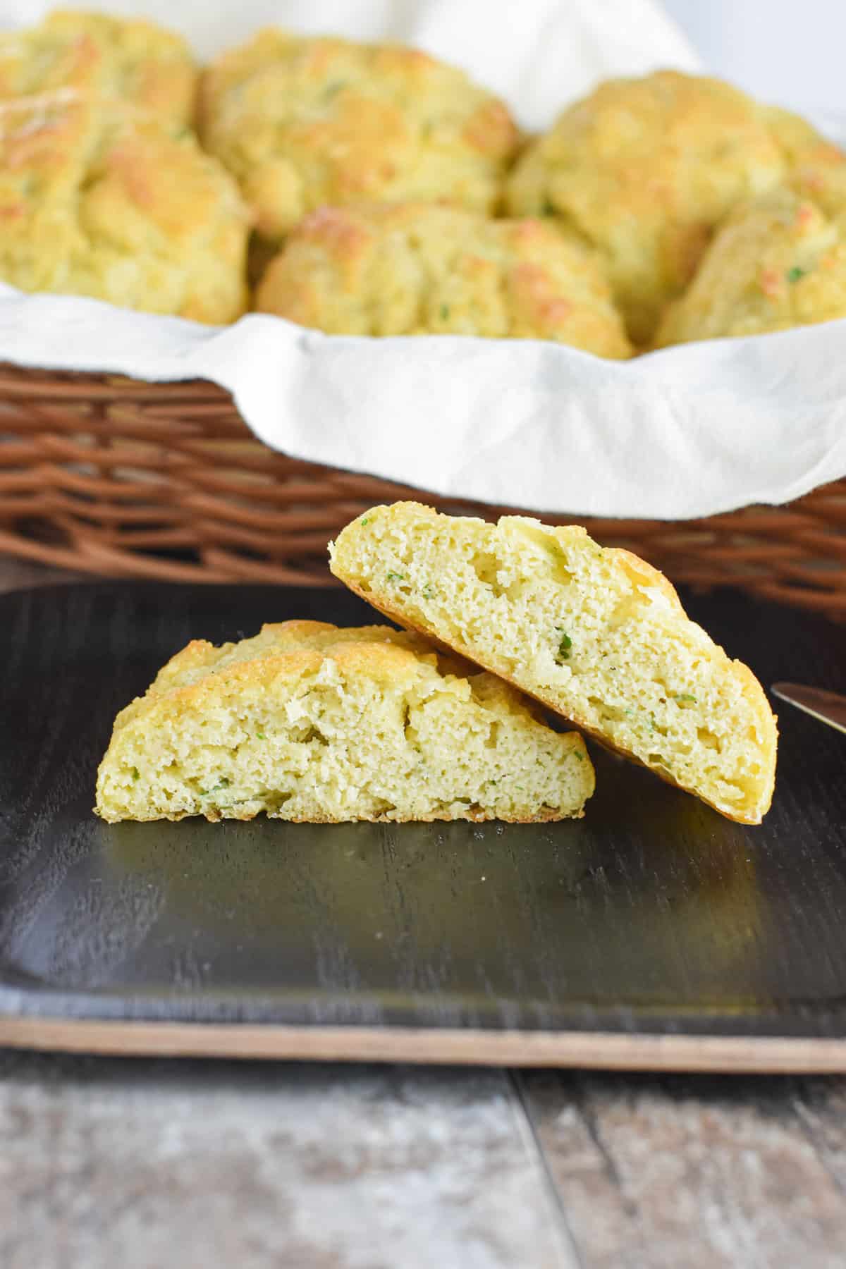 An open biscuit on a plate with a basket of more biscuits behind it.