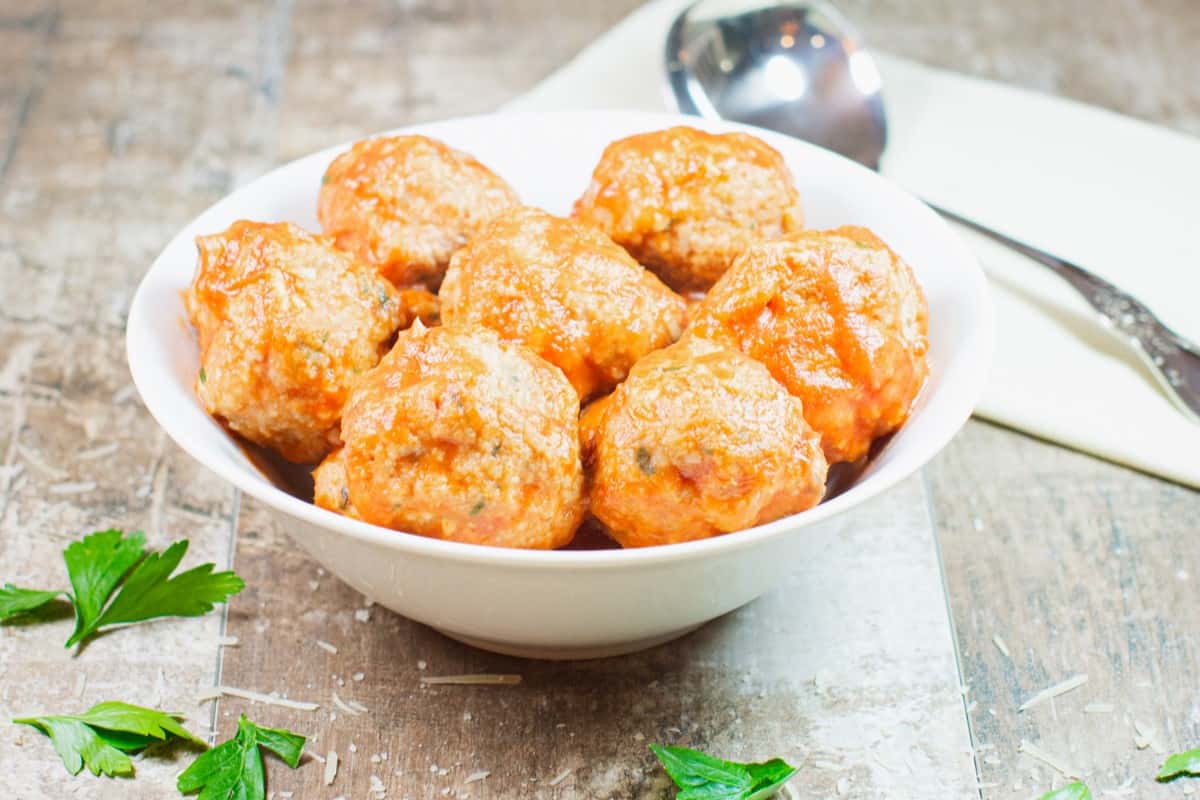 front view of a bowl of sauced baked turkey meatballs.