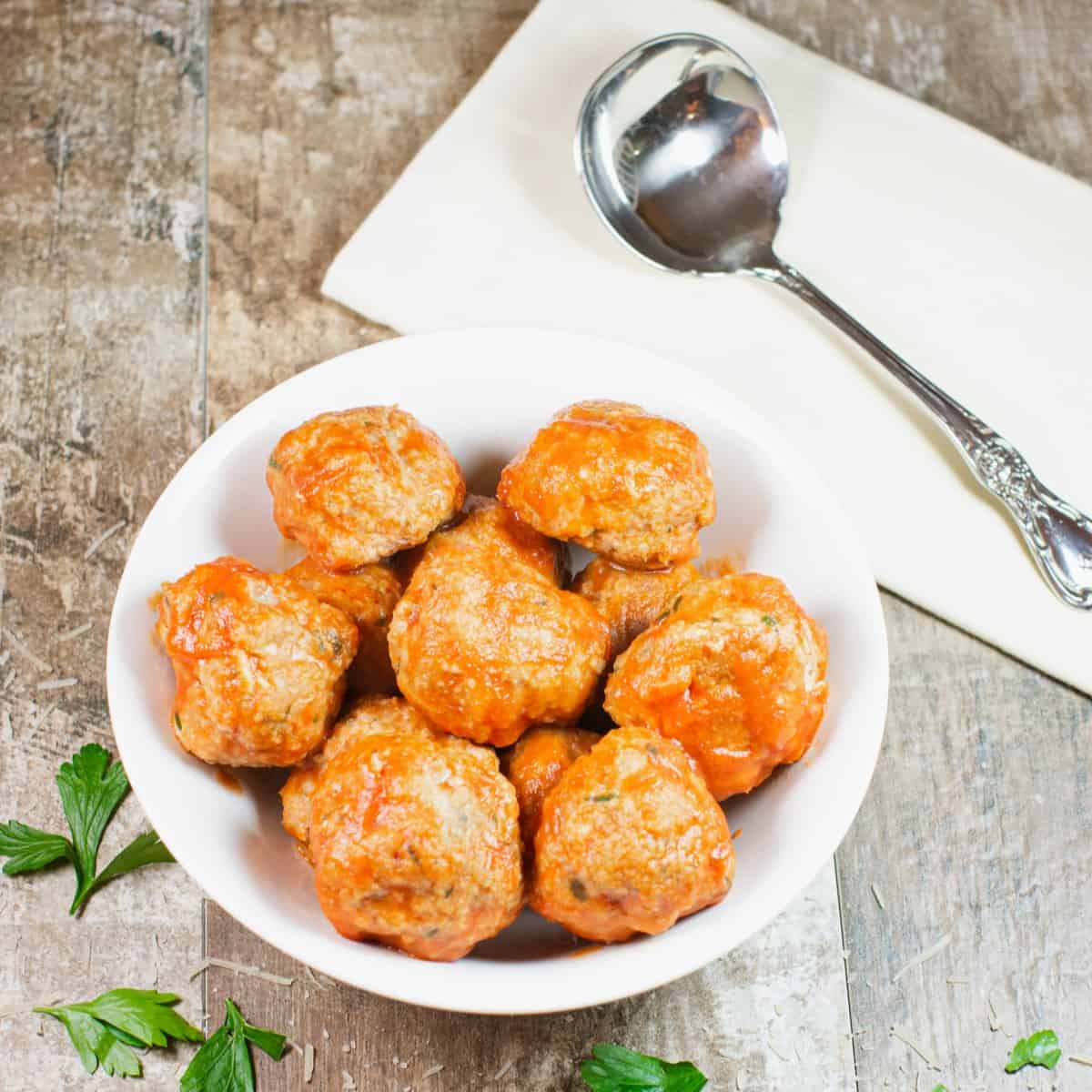 close-up overhead of sauced turkey meatballs in a white bowl.