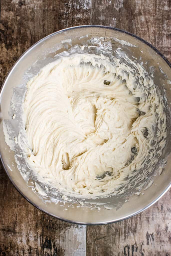 Frosting in a mixing bowl after adding and mixing in powdered sugar, pumpkin puree, cinnamon, and vanilla.