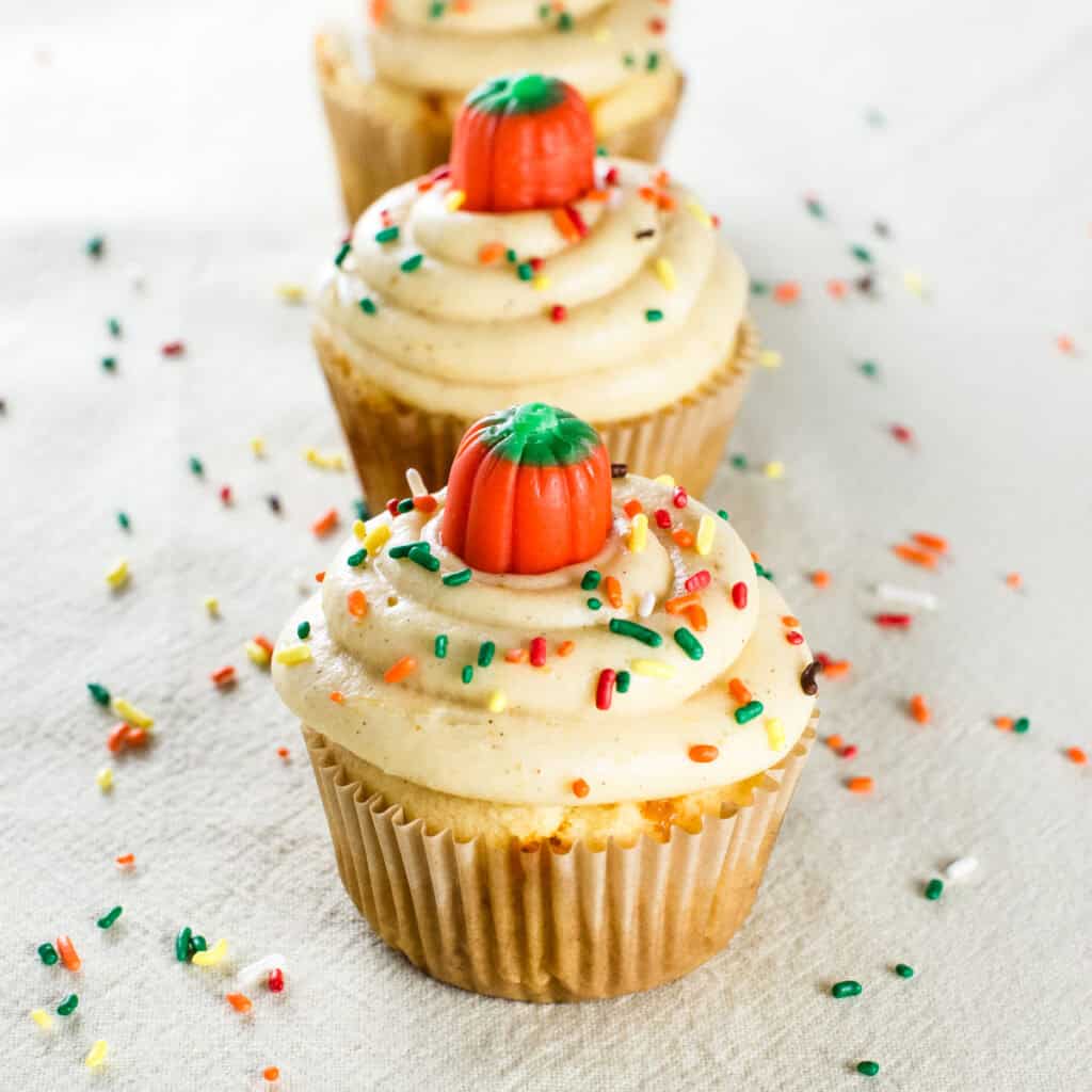 Cake mix cupcakes with pumpkin cream cheese frosting decorated with fall candies and sprinkles.