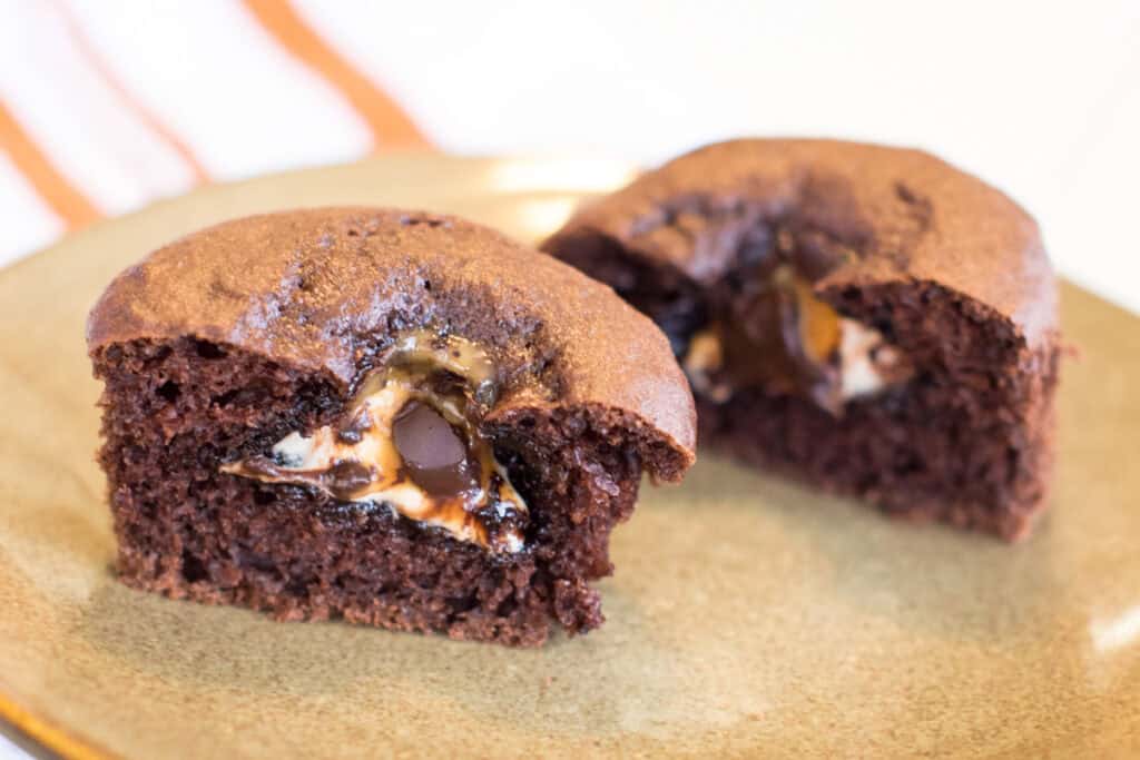 A cupcake cut in half on a plate to show the candy inside.