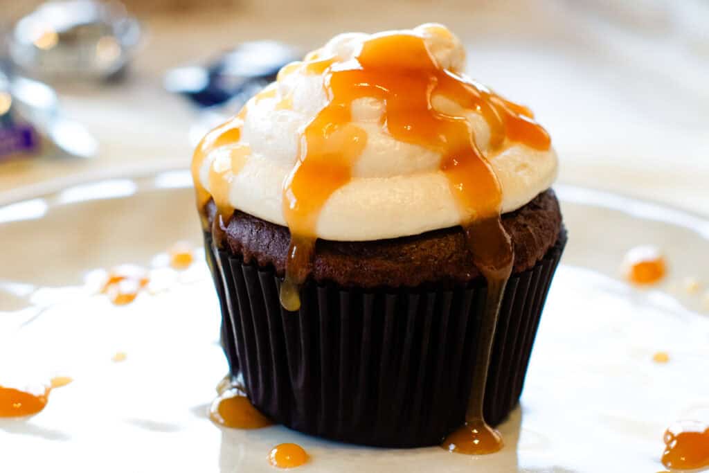 A close-up of a frosted cupcake with caramel drizzle on top.