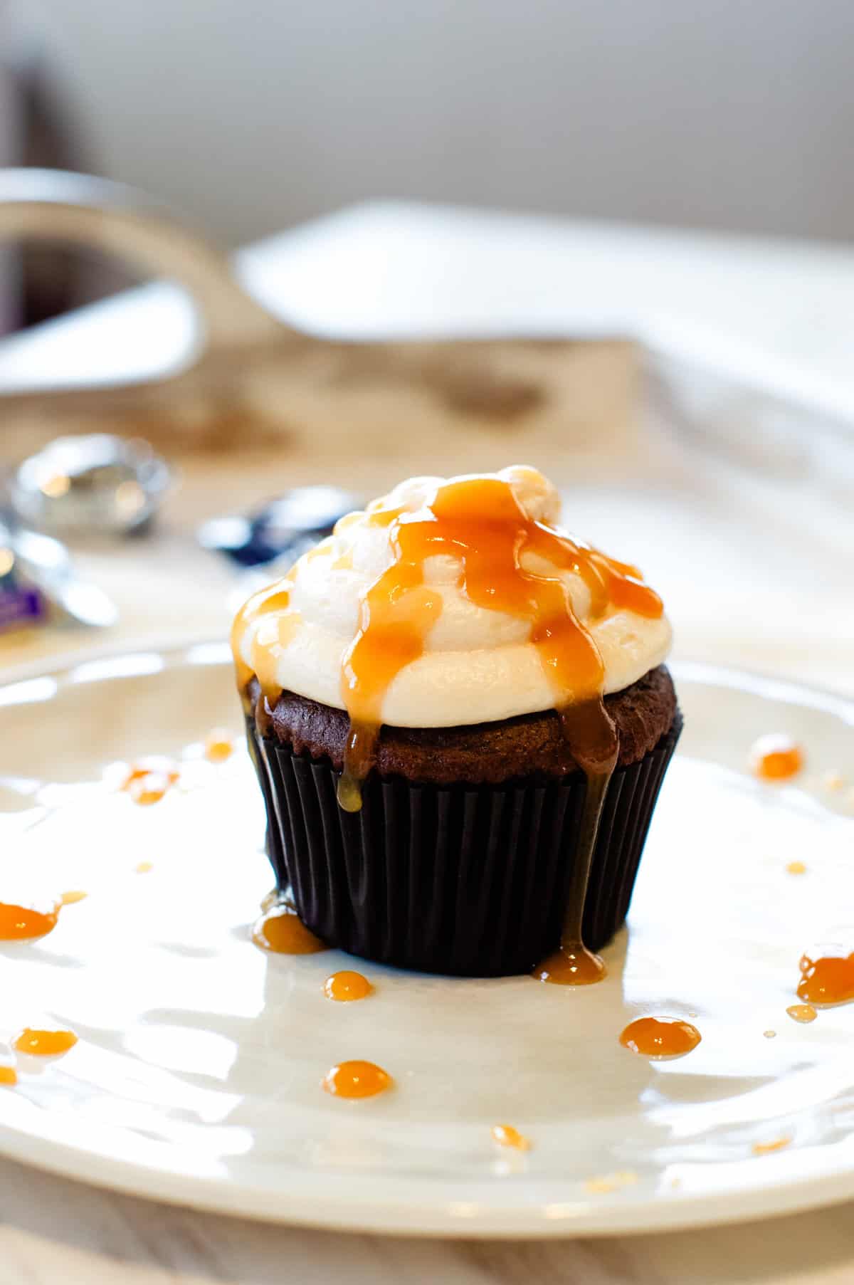 Milky Way Midnight Cupcake on a plate with caramel drizzle on top and on the plate.