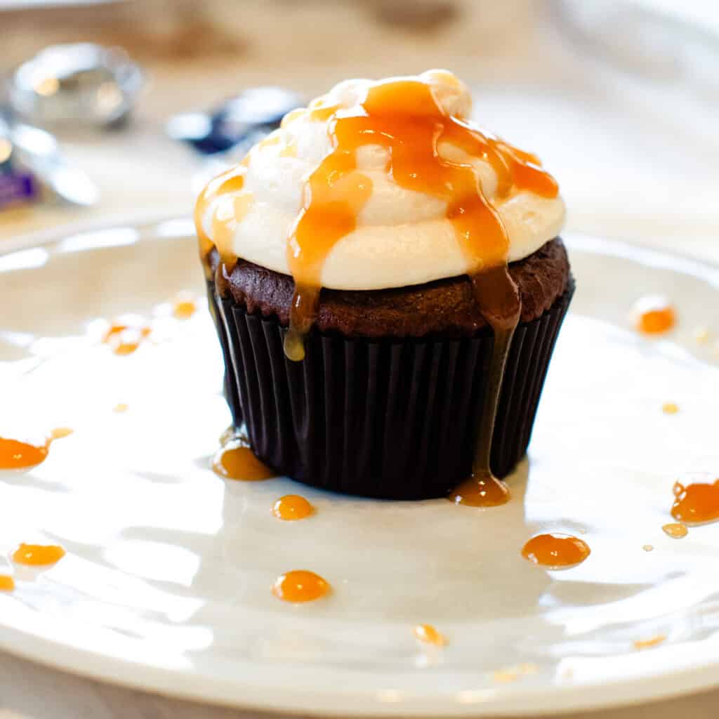 A Milky Way Cupcake with Caramel Frosting on a plate with caramel drips on the plate.