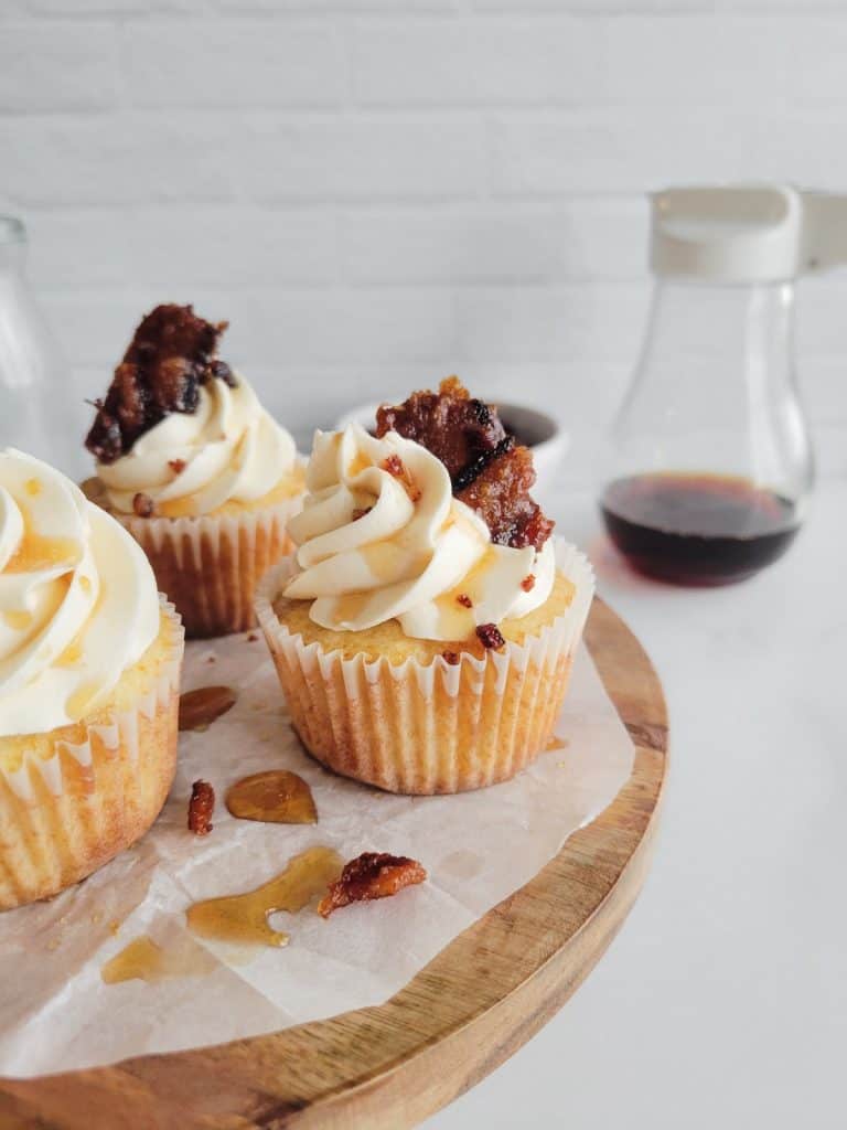 Maple bacon cupcakes on a circular wooden platter.