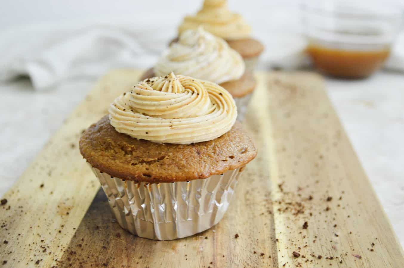 Caramel macchiato cupcakes on a wooden board.