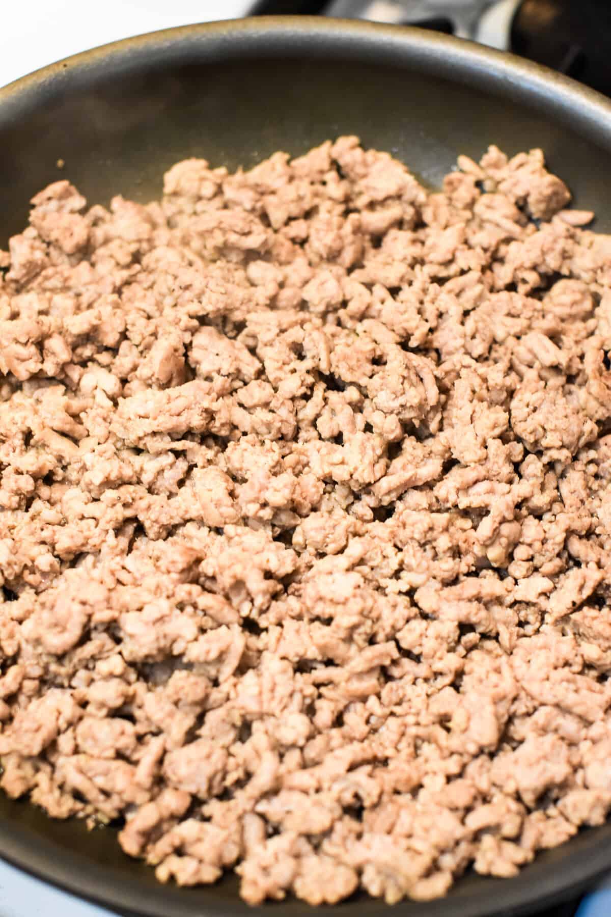 Ground pork cooking in a skillet.