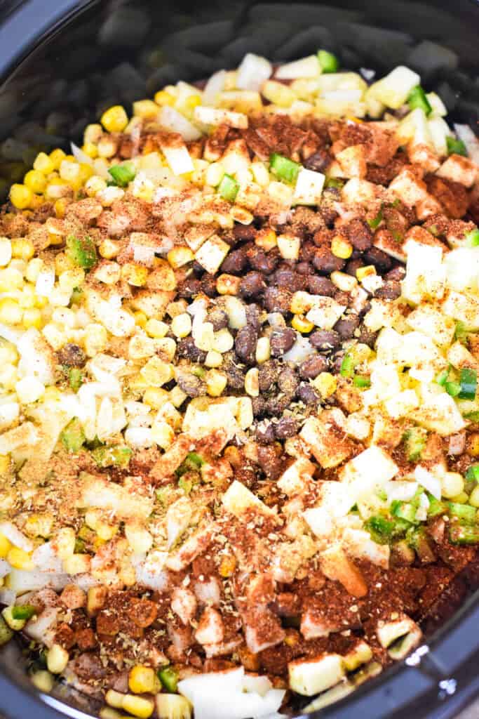 Ingredients for ground pork and black bean chili stirred together in a slow cooker.