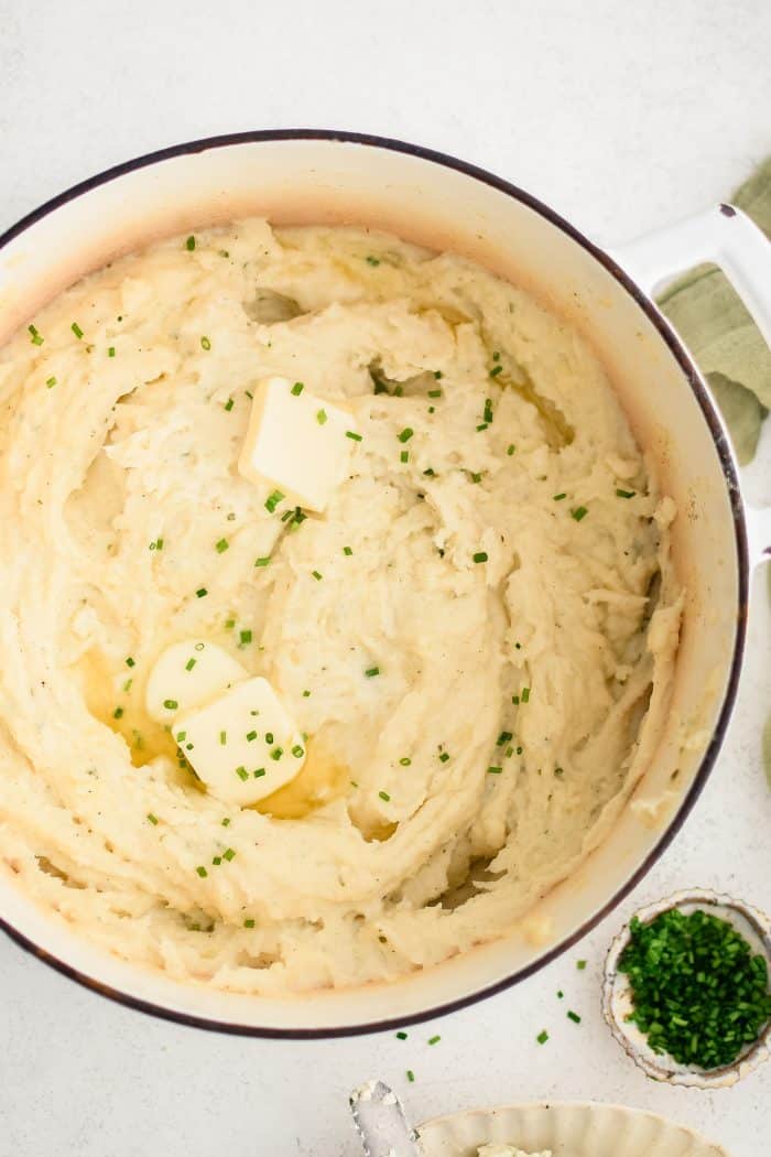 Boursin mashed potatoes in a pot with pats of butter in it.