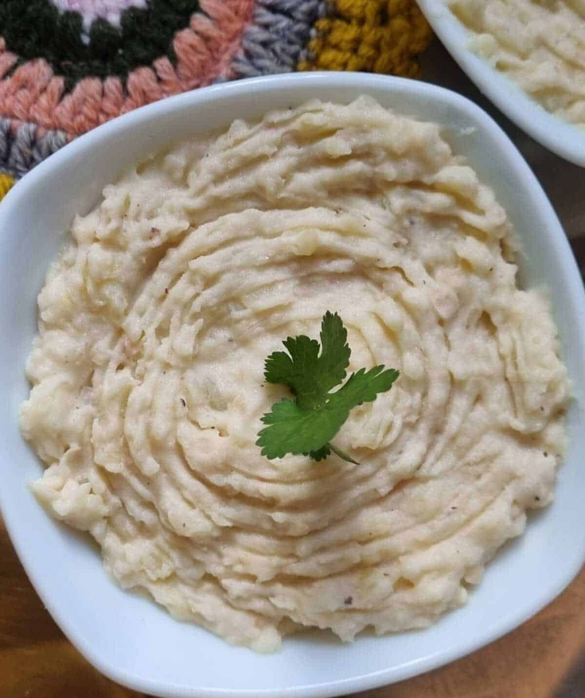 Protein mashed potatoes in a white dish with parsley garnish on top.