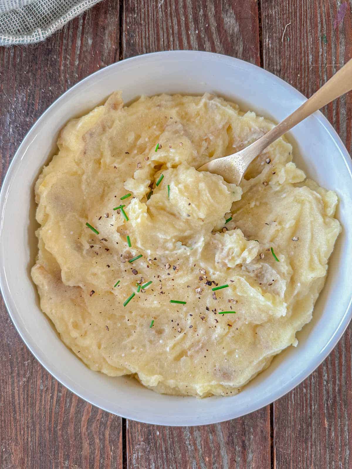 Cottage cheese mashed potatoes in a white bowl with a fork in it.