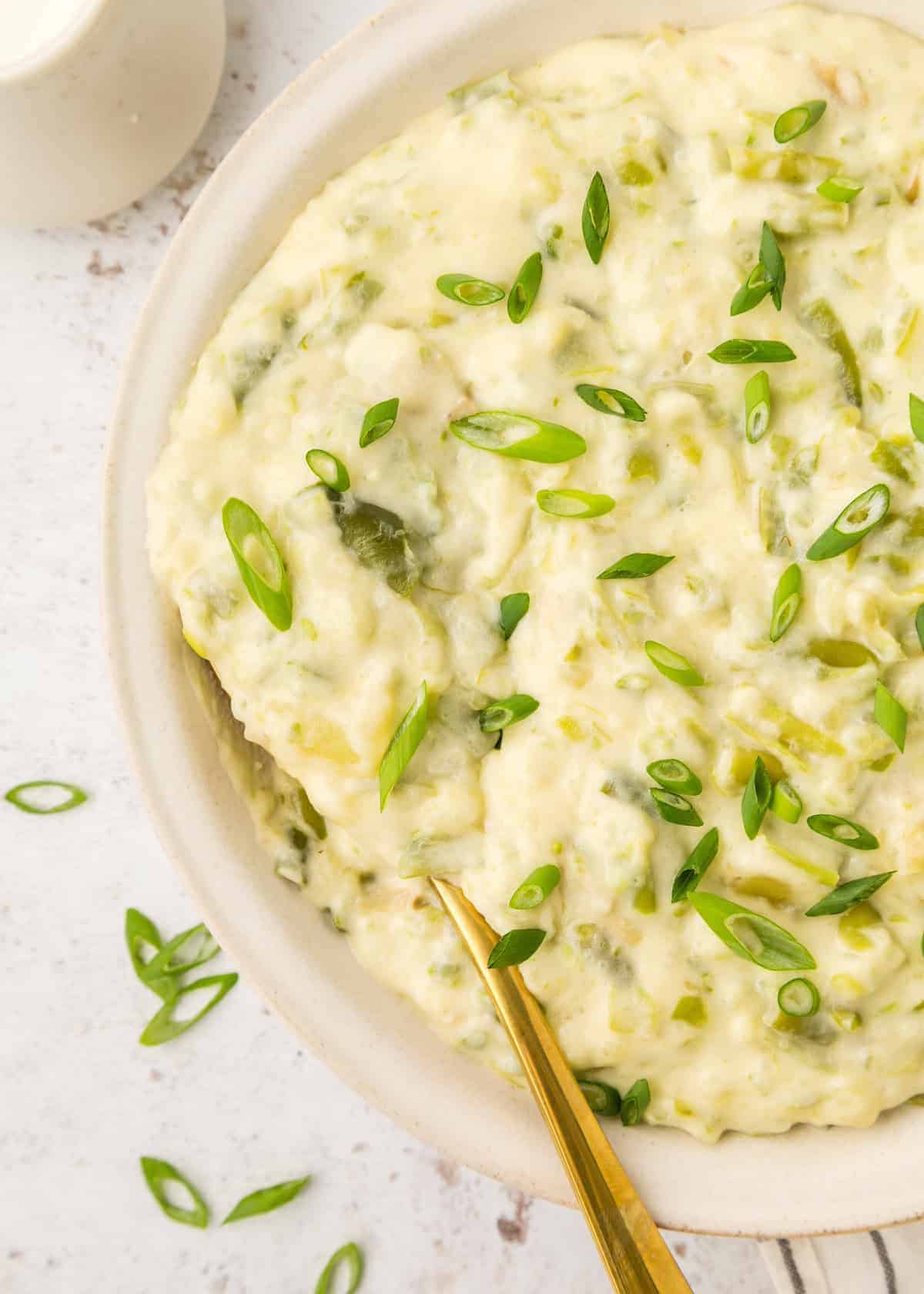 Green bean mashed potatoes in a white bowl with a spoon in it.