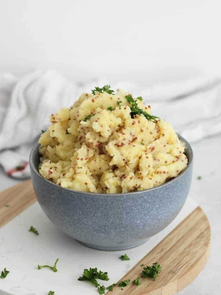 A blue bowl filled with wholegrain mustard mashed potatoes.