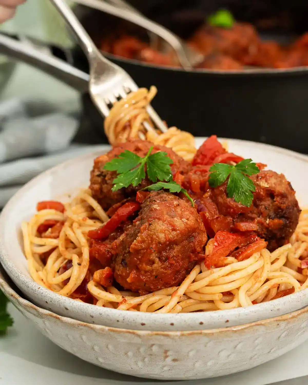 Beyond meatballs on top of spaghetti in a bowl with a fork grabbing some.