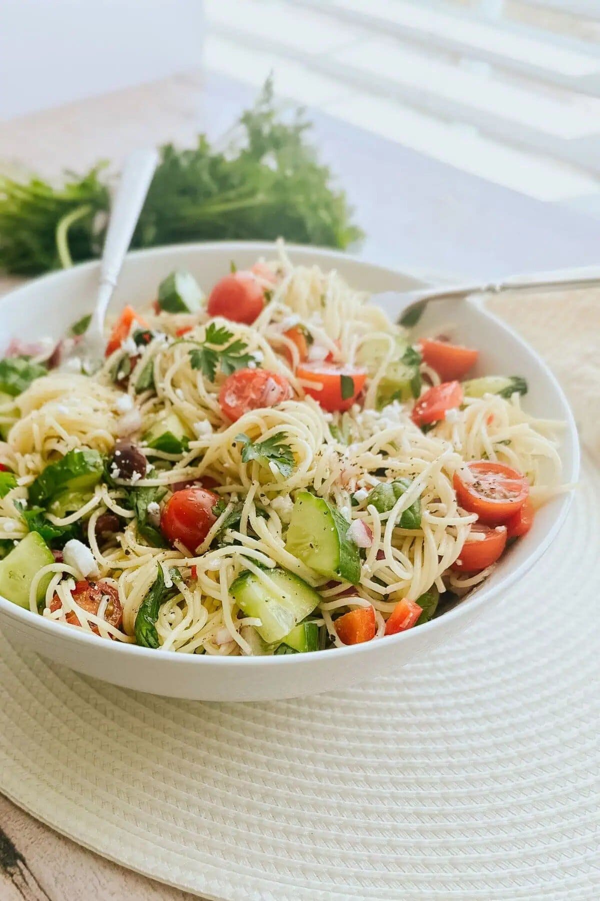 A bowl of angel hair pasta salad with two forks in it.