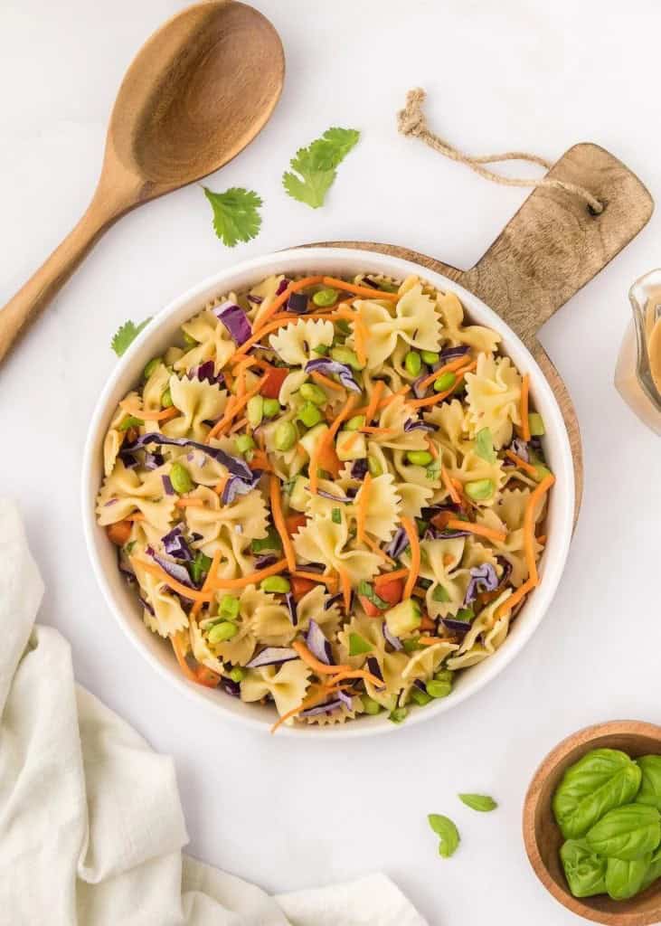 Thai pasta salad in a white bowl on a wooden paddle.