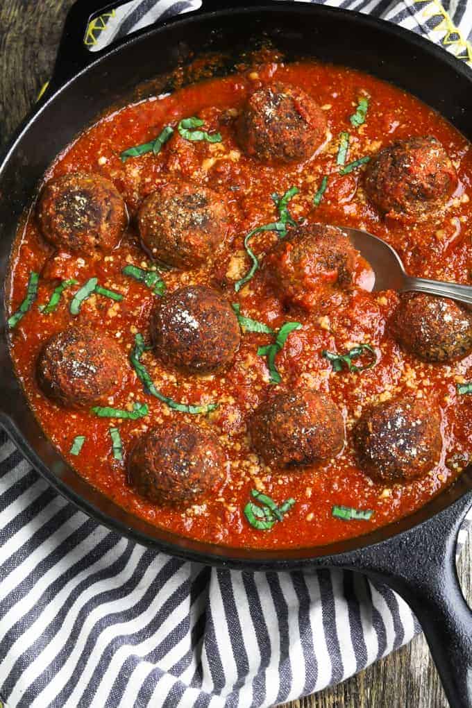 Vegan meatballs and tomato sauce in a skillet on a kitchen napkin.