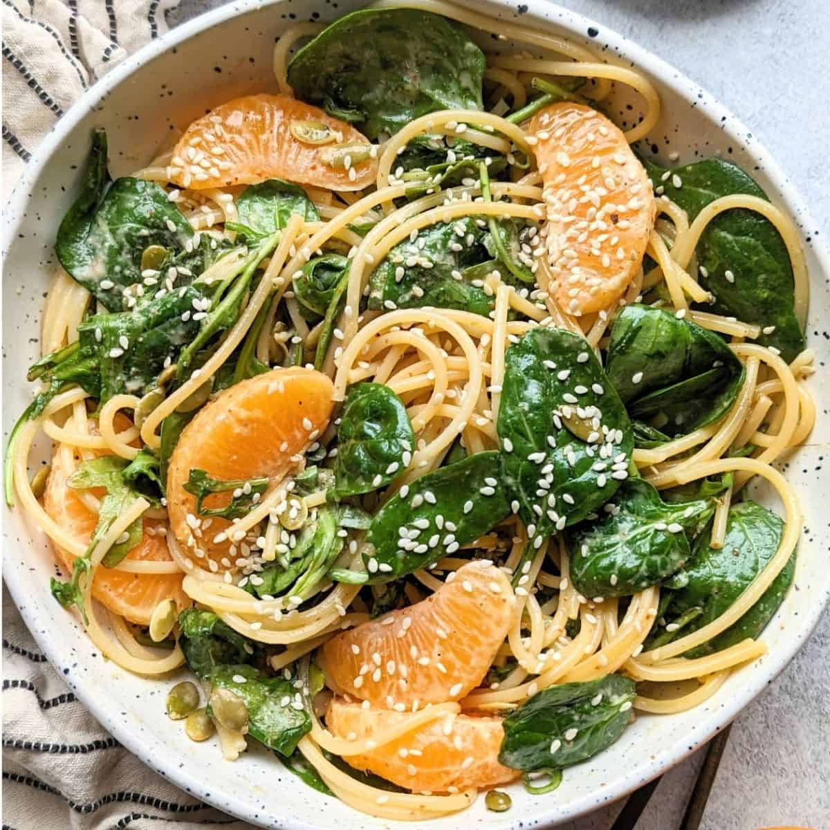 Orange sesame noodle salad in a white serving bowl.