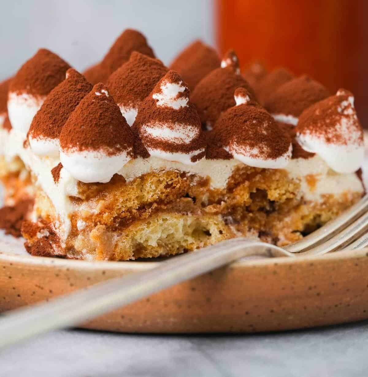 A slice of vegan tiramisu on a plate with a fork.