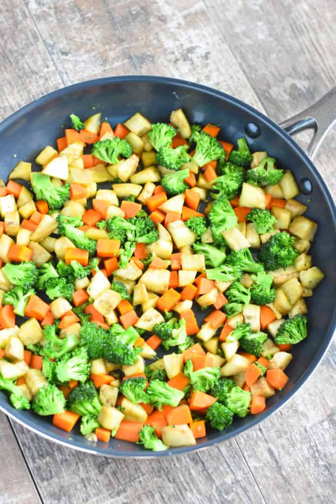 Cooked broccoli, eggplant, and carrots in a nonstick skillet.