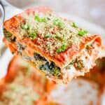 A close-up of slice of lasagna being held up on a spatula.