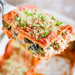 A close-up of slice of lasagna being held up on a spatula.
