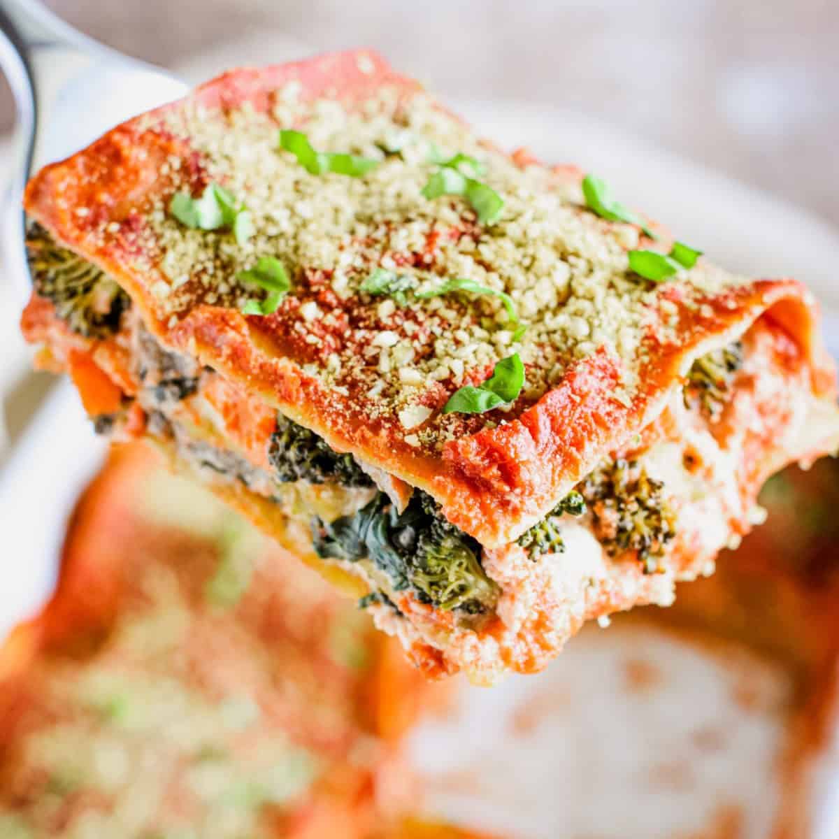 A close-up of slice of lasagna being held up on a spatula.