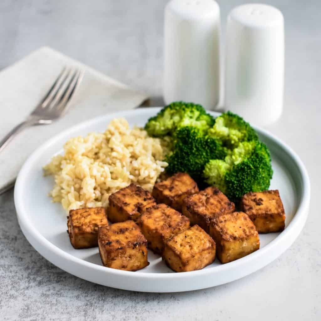 A white plate with tofu, rice, and broccoli.