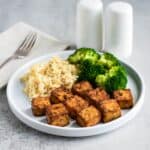 A white plate with tofu, rice, and broccoli.