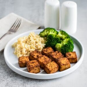 A white plate with tofu, rice, and broccoli.